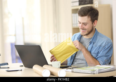 Imprenditore aprendo una busta imbottita in un piccolo ufficio o a casa Foto Stock