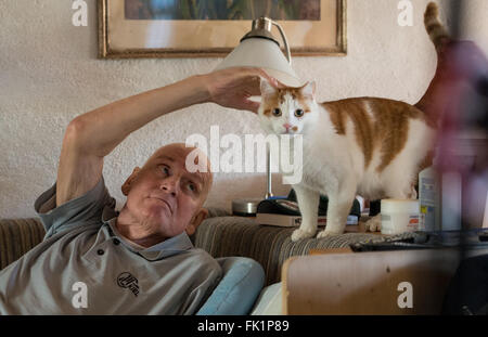 Bad Toelz, Germania. 02Feb, 2016. Ex giocatore professionale del hockey di ghiaccio Lorenz Funk animali domestici il suo gatto fortunato nella sua casa di Greiling vicino a Bad Toelz, Germania, 02 febbraio 2016. Il funk è stato membro del West team nazionale tedesco che ha vinto la medaglia di bronzo del 1976 Olimpiadi invernali di Innsbruck, in Austria. Sei mesi fa, Lenzo è stato diagnosticato un cancro. Foto: Matthias esitano di fronte/dpa/Alamy Live News Foto Stock