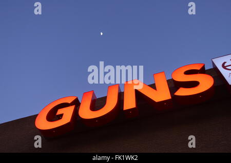 Segno rosso dicendo le pistole contro un cielo blu con la luna in Phoenix, Arizona Foto Stock