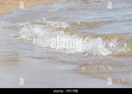 Un piccolo mare wave rotola su una spiaggia di sabbia, close-up Foto Stock