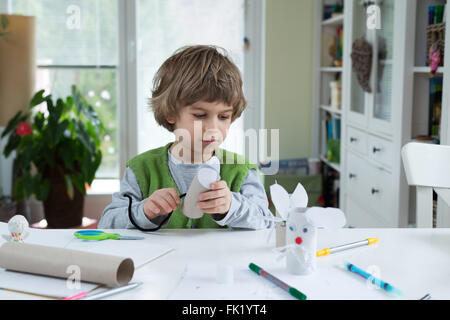 Little Boy essere creativi rendendo in casa dei giocattoli di carta. Il supporto di creatività, imparare facendo, di apprendimento attraverso l'esperienza. Foto Stock