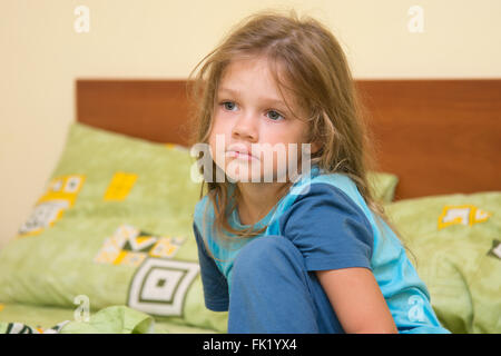 Funny cinque anni di ragazza risveglio seduta sul letto in pigiama Foto Stock