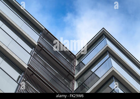 Frammento astratto di architettura moderna, pareti di cemento e vetro blu su sfondo con cielo nuvoloso Foto Stock