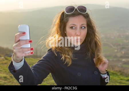 Ragazza tenendo un selfie su una escursione al tramonto Foto Stock