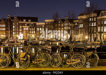 Una vista lungo il canale Waalseilandgracht ad Amsterdam di notte con la bici come il fuoco principale in primo piano. Foto Stock