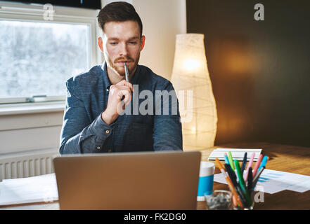 Commercio serio uomo che lavora sul computer portatile mentre cerchi concentrati Foto Stock