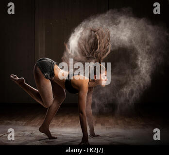 Ballerina ballando con farina su sfondo scuro Foto Stock