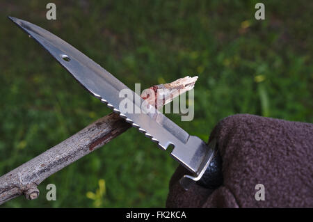 Utilizzando un coltello di sopravvivenza per rendere una freccia. Sopravvivenza, all'aperto e tema militare Foto Stock