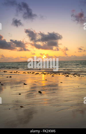 Il sole sorge su una spiaggia vuota e sull'oceano aperto Foto Stock