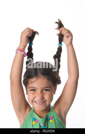 Bambina sta tenendo il suo pigtail alta per divertimento su sfondo bianco Foto Stock