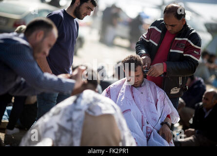 Idomeni, Grecia. 06 Mar, 2016. Gli uomini si tagliare i capelli al campo profughi al confine Greek-Macedonian vicino Idomeni, Grecia, 06 marzo 2016. Solo pochi rifugiati dalla Siria e Iraq vengono lasciate oltre confine in Macedonia ogni giorno. Foto: KAY NIETFELD/dpa/Alamy Live News Foto Stock