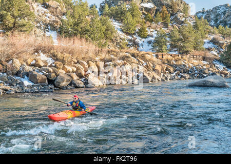 Kayaker senior in un kayak whitewater paddling a monte - Arkansas River, Colorado nel paesaggio invernale Foto Stock