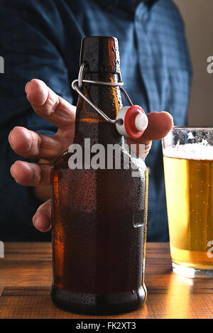 Primo piano di un uomo di raggiungere per un vecchio swing top bottiglia di birra. Foto Stock