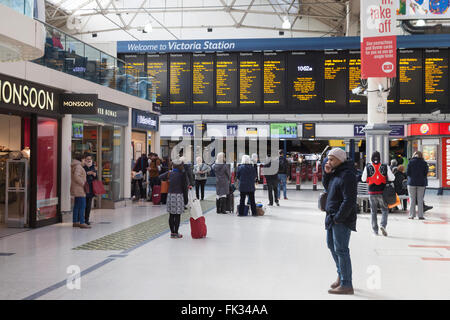 Victoria Station London - persone nell'atrio che guardano il bordo di partenza; Victoria Train Station, London UK Foto Stock