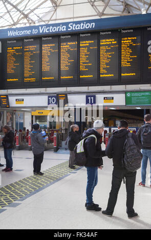 Victoria Station London - persone nell'atrio che guardano il bordo di partenza; Victoria train station, London UK Foto Stock