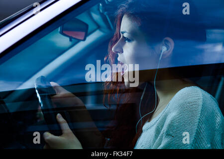 Urlando donna con gli auricolari alla guida di una macchina Foto Stock