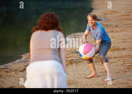 Coppia felice giocando a pallavolo con palla spiaggia in estate Foto Stock