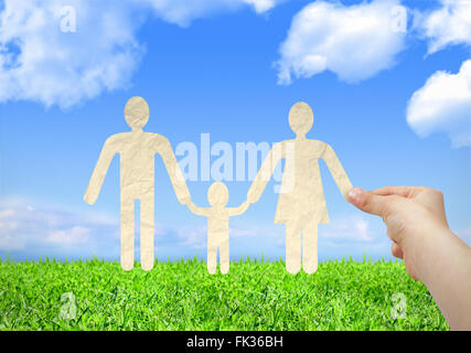 Mano che regge il taglio della carta famiglia con sfondo cielo Foto Stock