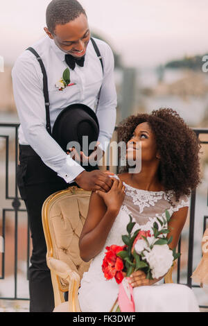 Esotici africani sposa e lo sposo tenendo le mani sulla terrazza Foto Stock