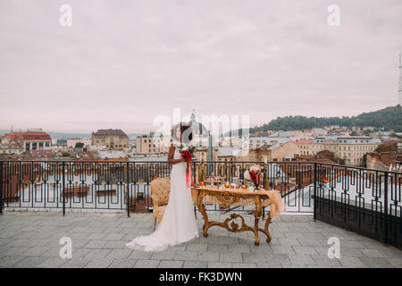 Bella sposa africana con bouquet di nozze in mani in piedi sulla terrazza Foto Stock