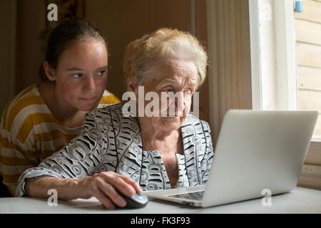 La nipote insegna la nonna di digitare sul computer portatile. Foto Stock