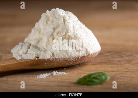 Farina bianca in cucchiaio su sfondo di legno con profondità di campo Foto Stock