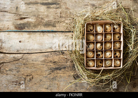 Pasqua Sfondo legno con scatola di uova di quaglia all'interno del nido di fieno Foto Stock