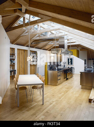Vista interna di una moderna cucina e sala da pranzo in camera mansardata con pavimento in legno e a capriate di legno Foto Stock