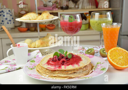 Pila di frittelle morbido naturale con gelatina di lamponi con appena fatto i frullati di lampone e kiwi serviti per colazione Foto Stock