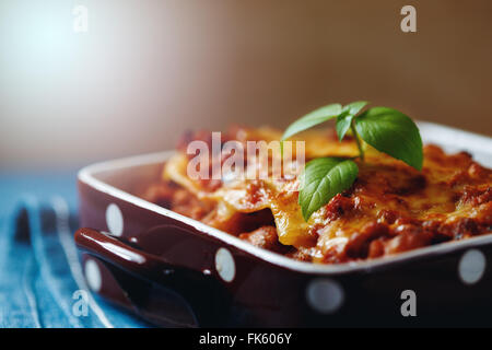 Il cibo italiano. Gustosi piatti caldi appena sfornati serviti di lasagne con basilico erba. Close-up, il fuoco selettivo. Foto Stock