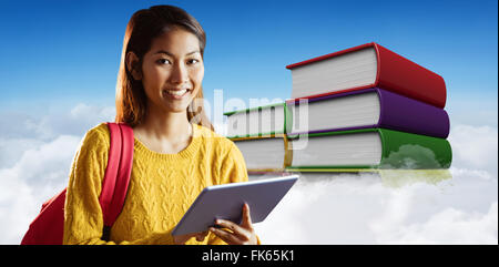 Immagine composita di sorridere asian studentessa utilizzando tablet Foto Stock