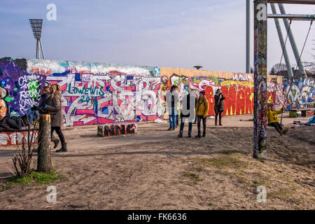 I turisti a piedi passato coperto di graffiti muro di Berlino a Mauerpark, Berlino Foto Stock