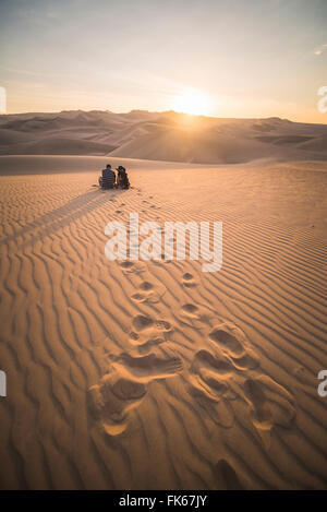 Giovane e guardare il tramonto sopra le dune di sabbia del deserto di Huacachina, Regione di Ica, Perù, Sud America Foto Stock