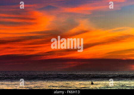 Lone surfer e tramonto nuvole off Playa Hermosa surf beach, sud della penisola di Nicoya, Santa Teresa, Puntarenas, Costa Rica Foto Stock