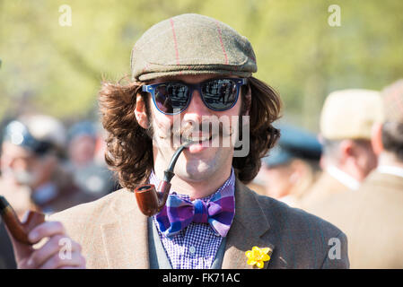 Giovane uomo con i baffi in abbigliamento Vintage, occhiali da sole e un tubo di fumo in Tweed Run (corsa in bicicletta con uno stile) Foto Stock