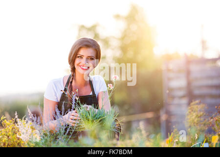 Giovani giardiniere in giardino con varie piante, carattere solare Foto Stock