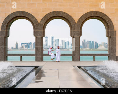 Due uomini locali e sullo skyline di Doha distretto finanziario presso il Museo di Arte Islamica di Doha in Qatar Foto Stock