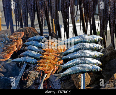 Sardine su uno spiedino di legna da ardere in spiaggia Foto Stock