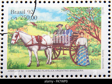 Timbro stampato in Brasile dedicato al costume gauchos, mostra giovane in carrozza trainata da cavalli e donna Foto Stock