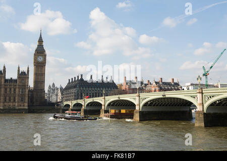Rimorchiatore tirando una chiatta con i contenitori di spedizione lungo il fiume Tamigi a Londra. Passando al Westminster Bridge Foto Stock