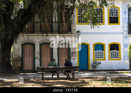 La gente seduta su una panchina nel parco matrice e case coloniali in centro storico Foto Stock