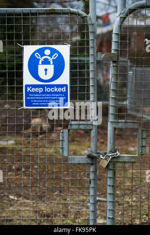 La salute e la sicurezza di mantenere bloccato segno sulla recinzione perimetrale di un sito in costruzione, Bicester, Oxfordshire, Inghilterra Foto Stock