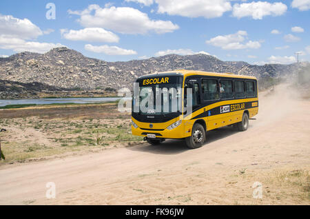 Scuola bus viaggia su una strada sterrata nel villaggio Gargalheiras Foto Stock