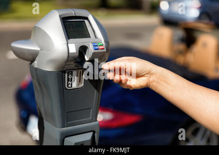 Stretta di mano femmina inserimento carta di credito nel parcometro tempo all'aperto sulla strada. Messa a fuoco selettiva su mano tenendo la scheda. Foto Stock