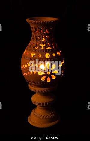 Lampada artigianale con una candela accesa all'interno su sfondo nero Foto Stock