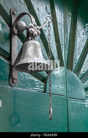 In vecchio stile bell come campanello verde sulla porta di legno. Foto Stock