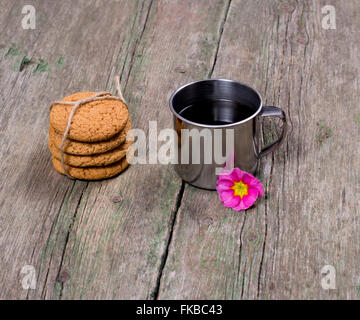 L'acciaio tazza di caffè decorato con un fiore e un collegamento di cookie Foto Stock