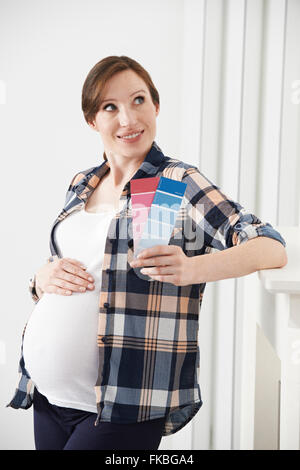 Donna incinta scegliendo la combinazione di colori per la stanza del bambino Foto Stock