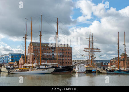 Gloucester quays con alte masted le navi ormeggiate in alto e mostra vecchi magazzini restaurati, Gloucestershire Foto Stock