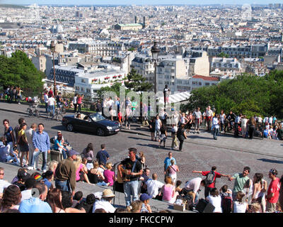 Turisti e buskers a Montmartre si affaccia sul panorama di Parigi. Foto Stock